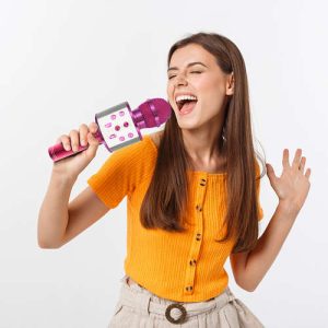 Mlada ženska sproščeno poje na zabavi, uporablja roza karaoke mikrofon z enostavnim upravljanjem